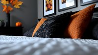 Cozy autumn bedroom decor with orange knit pillows, black floral cushions and fall maple leaves against dark wall with framed artwork on white bedding.