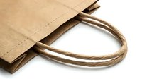 Brown kraft paper shopping bags with twisted rope handles isolated on white background for eco-friendly retail packaging and sustainable commerce.