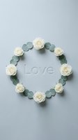 Floral wreath of white roses and eucalyptus leaves arranged in a circle with Love text on soft gray background for wedding design.