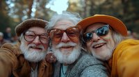 Senior friends taking cheerful selfie outdoors, enjoying retirement together. Active elderly men with beards and glasses smiling at camera in autumn park.