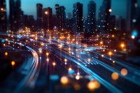 Night cityscape with light trails from traffic on highway, illuminated skyscrapers in background, and bokeh effect creating dreamy urban atmosphere.