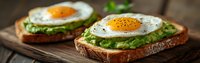 Toasted bread slices topped with mashed avocado and sunny side up eggs on rustic wooden board, panoramic banner format for breakfast or brunch menu.