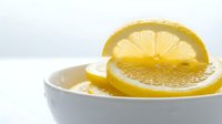 Fresh lemon slices in white ceramic bowl on clean background for healthy cooking and citrus fruit concepts in kitchen photography.