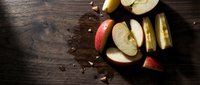 Fresh apple slices with cinnamon spice on rustic wooden background for healthy snacking and autumn cooking recipes.