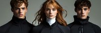 Young fashion models wearing black turtleneck jackets pose for dramatic portrait against gray background. Red-haired woman stands between two men with styled hair.