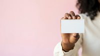 African American male professional holding blank white business card against pink background, suitable for corporate branding and marketing materials.