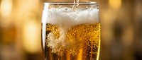 Refreshing cola beverage with ice cubes in a clear glass against a warm, blurred background, perfect for beverage advertising and restaurant menus.