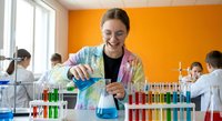 Young female scientist in lab coat conducting chemical experiment with colorful test tubes and beakers in modern laboratory setting.