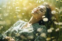 Young woman with closed eyes relaxing in summer meadow among blooming daisies, sunlit dreamy atmosphere captures peaceful natural wellness moment.