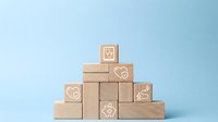Wooden blocks arranged in pyramid shape with healthcare icons on light blue background, symbolizing medical insurance and health protection concept.