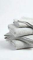Stack of folded light gray and beige towels with various textures displayed against white background for home decor, spa, and laundry design projects.