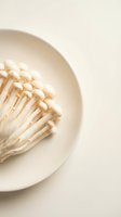 Enoki mushrooms arranged in white ceramic bowl on neutral background, isolated for culinary, food styling, recipe, and ingredient photography use.