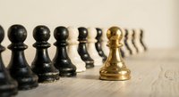 Golden chess pawn standing out among black pawns on wooden surface, leadership and uniqueness concept for business strategy and competitive advantage.