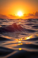 Ocean wave at sunset with golden sun reflection on dark water surface creating dramatic seascape with glowing orange sky and rippling textures.