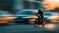 Motorcyclist in black helmet riding sport bike on urban street with motion blur effect creating dynamic sense of speed at dusk.