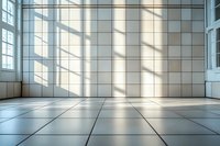 Empty modern interior with white tiled walls and floor, large windows casting dramatic diagonal shadows, creating minimalist architectural space.