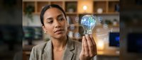 Professional Hispanic businesswoman holding glowing brain lightbulb representing innovation and creative thinking in modern office environment.