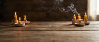 Lit candles arranged on rustic wooden surface with dark chalkboard background, creating warm ambiance for wellness, meditation, spirituality, or relaxation themes.