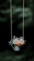 Vintage watering can hanging on rope with peach roses and eucalyptus leaves against dark background. Garden decoration concept for weddings and events.