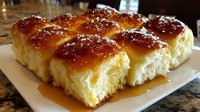 Golden brioche dinner rolls with glossy egg wash finish arranged on white plate, perfect for holiday meals and bakery displays.