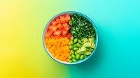Fresh poke bowl with diced salmon, mango, edamame, avocado and kale on vibrant yellow-turquoise gradient background. Healthy food concept.