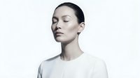 Young East Asian woman with fair skin and dark hair styled back, wearing a light gray t-shirt, eyes closed in serene expression against white background. Suitable for wellness, skincare, and lifestyle marketing.