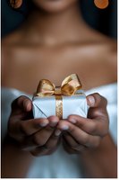 African American woman's hands holding small white gift box with golden glitter bow against blurred background, creating romantic holiday atmosphere.