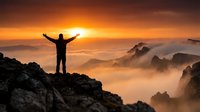 Silhouette of triumphant hiker with raised arms celebrating success on mountain peak at golden sunrise with misty valleys and dramatic orange sky below.
