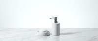 Minimalist bathroom accessories set with white ceramic soap dispenser and dish on marble surface for home decor and wellness design projects.
