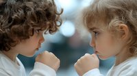 Two young children with curly hair facing each other in white clothing, showing sibling bond and childhood friendship in soft natural light.