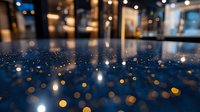 Blurred bokeh lights create magical atmosphere on dark blue surface with reflections and glowing spots, abstract background for festive designs and celebrations.