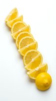 Diagonal row of fresh lemon slices with a whole lemon on white background, showcasing vibrant yellow citrus fruit for food and health design.