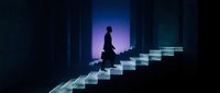 Silhouetted figure ascending illuminated staircase in dark corridor with blue and purple neon lighting, symbolizing career growth, ambition, and success in business and personal development.