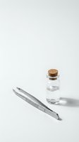 Small glass vial with cork stopper and metal tweezers on white background for laboratory research and scientific experiments.