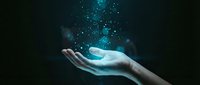 Open palm holding glowing cyan digital particles and sparkles against dark background for technology and innovation concepts.