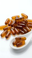 Amber gel capsules spilling from white spoon on clean background for pharmaceutical and supplement industry marketing materials.