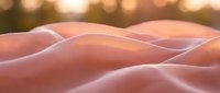 Soft pink fabric with gentle folds and warm golden bokeh lights creating dreamy atmosphere for textile and fashion design projects.