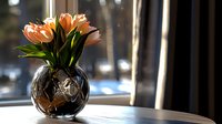 Orange tulips in decorative glass vase on windowsill with blurred urban background, suitable for home decor, spring themes, and interior design projects.