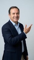 Confident middle-aged Caucasian businessman in navy suit pointing finger gesture on gray background isolated for professional marketing materials.