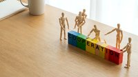 Wooden figurines arranged on colorful blocks spelling cooperation, symbolizing teamwork, collaboration, and business success on wooden surface.