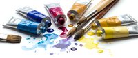 Acrylic paint tubes in blue, pink, yellow and gold with brushes and colorful paint strokes and splatters on white background for art projects.