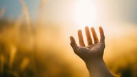 Hand reaching toward bright sunlight with warm golden rays and soft bokeh background creating hopeful spiritual atmosphere for wellness and inspiration concepts.