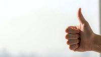 Hand showing thumbs up gesture against clean white background for positive feedback and approval concepts in business presentations.