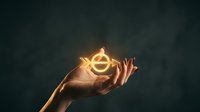 Hand holding glowing golden dollar sign symbol with light rays against dark background representing financial success and wealth management concepts.