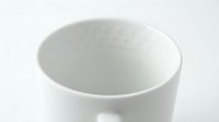 White ceramic mug with delicate embossed geometric pattern on rim, soft focus background, minimalist style for home decor and lifestyle design.