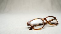 Tortoiseshell eyeglasses with brown frames resting on neutral fabric surface, suitable for optometry, vision care, eyewear retail, and healthcare marketing materials.