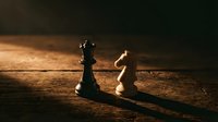 Chess pieces king and knight on wooden board with dramatic lighting creating long shadows in strategic game setup.