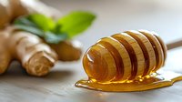 Wooden honey dipper with fresh golden honey dripping, ginger root and green leaves in soft natural light on white wooden background. For food blogs.
