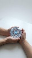 Male hands holding glowing mystical compass with ancient Nordic runes and symbols for spiritual guidance and navigation concepts.