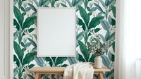 Modern interior with tropical leaf wallpaper, blank white frame mockup on wooden console table with decorative vase for home decor and design projects.
